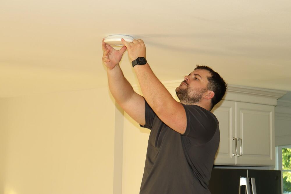 Technician installing wireless access point on ceiling